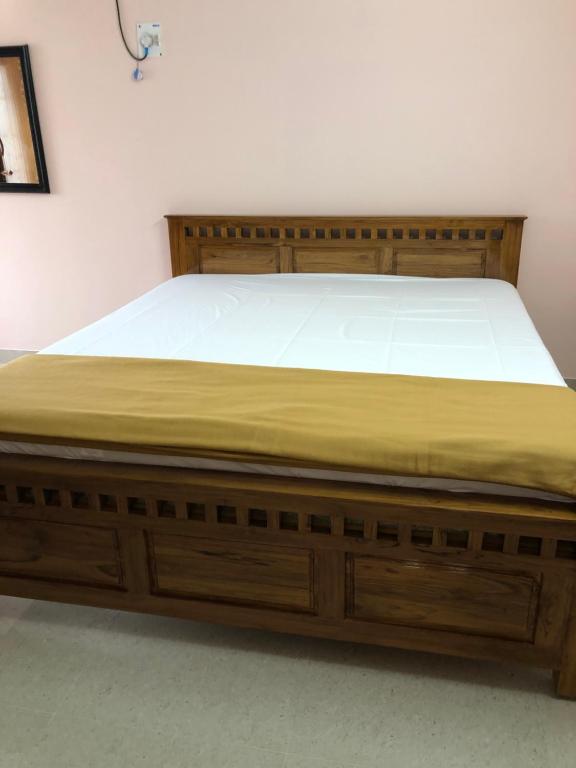 a bed with a wooden bed frame in a room at Tirumala Elite Homestay (near Railway station & Bustand) in Tirupati