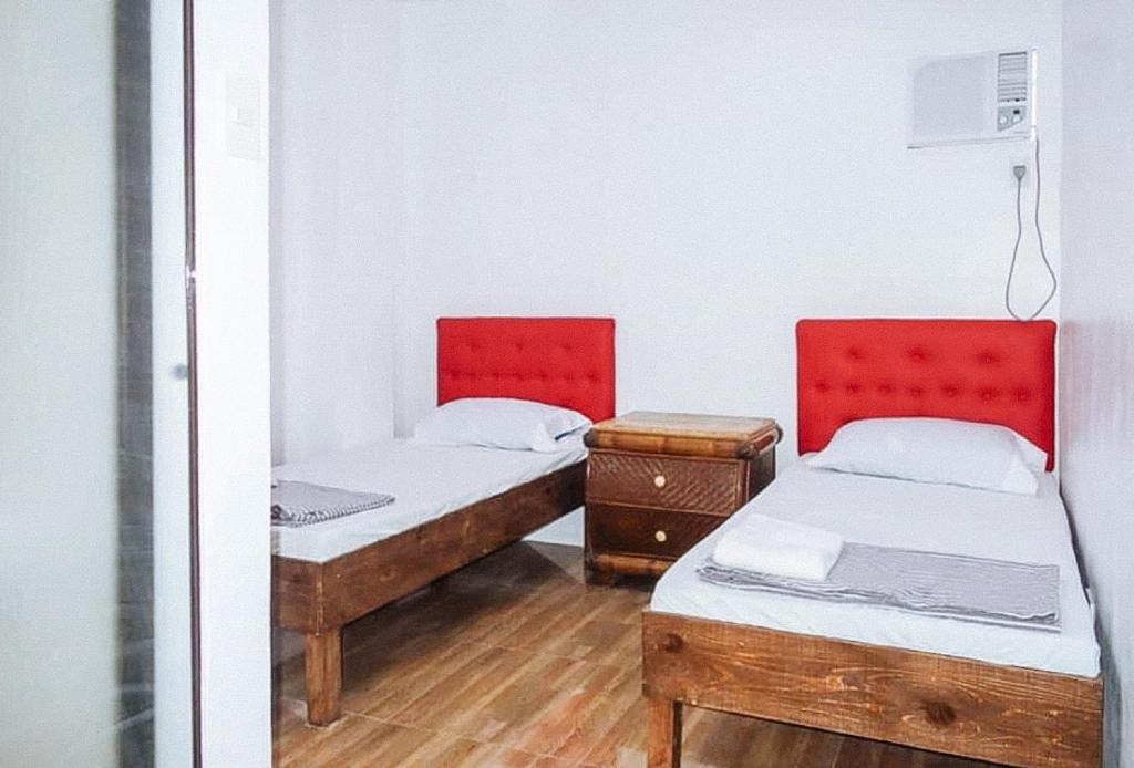 two beds in a small room with wooden floors at Magabelle Guesthouse in Cebu City