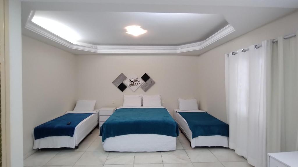 um quarto com 2 camas com lençóis azuis e brancos em Acomodações Anfitriã em Indaiatuba