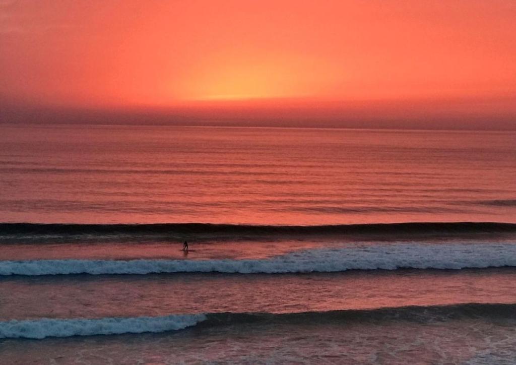 a person surfing in the ocean at sunset at L'Océan&Dunes vue à 180° en bord de plage in Lacanau-Océan