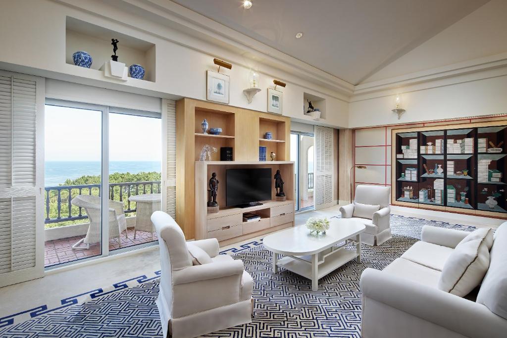 a living room with white furniture and a large window at The Shilla Jeju in Seogwipo