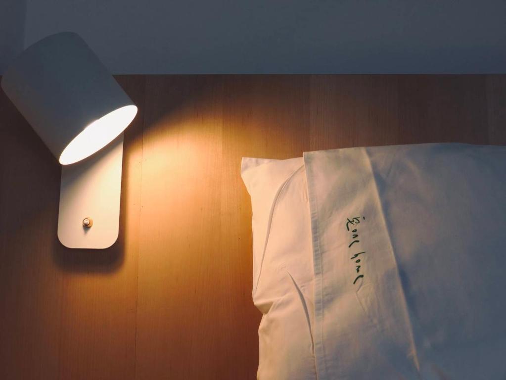a bed with a white pillow and a light on a wall at Kenting Onehome in Checheng