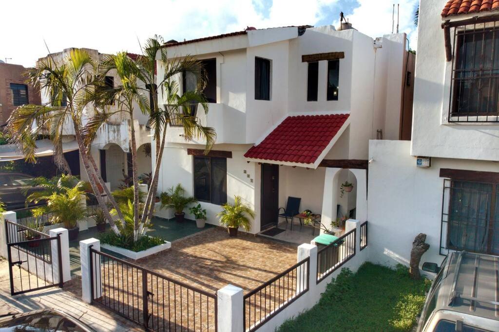 a white house with a fence and palm trees at Cómoda casa céntrica con alberca privada en Cancún in Cancún