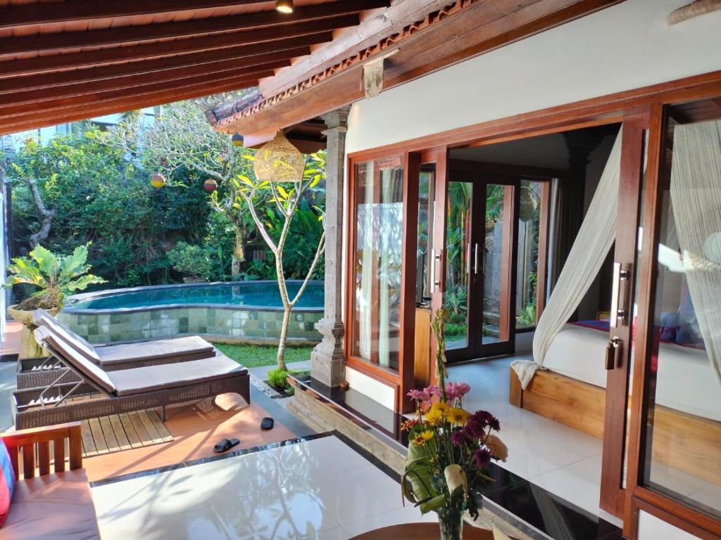 um pátio com uma mesa e cadeiras e uma piscina em Baruna Sari Villa em Ubud