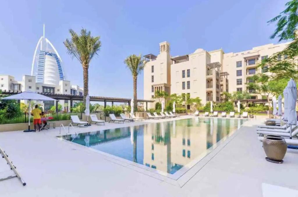 a pool at a hotel with palm trees and buildings at Madinat Jumeirah Living, MJL Dubai in Dubai