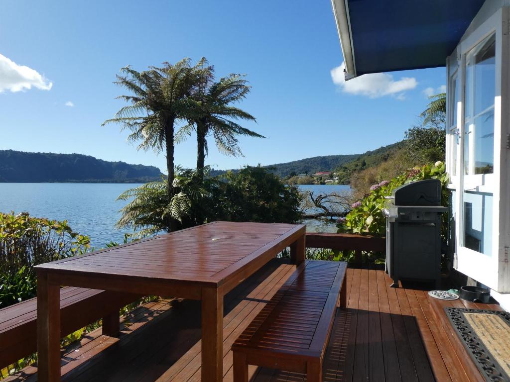 Rotoiti的住宿－The Blue Bach - Lake Rotoiti Holiday Home，木甲板配有桌子,享有水景