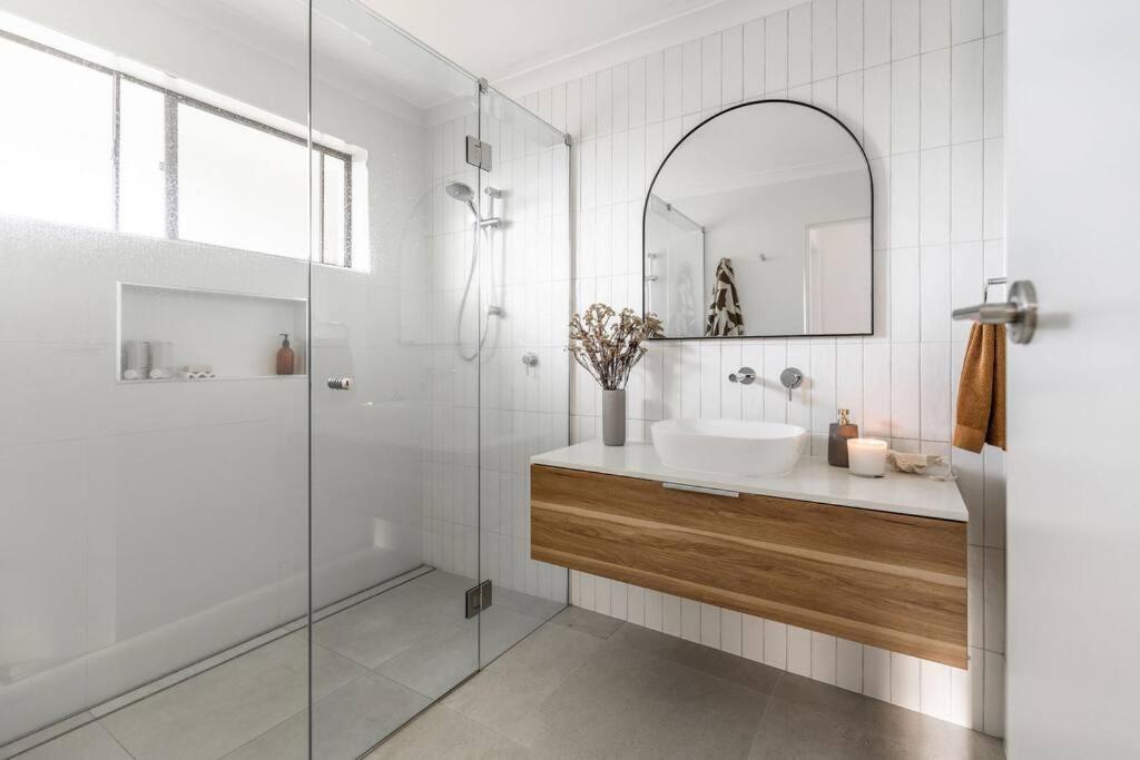 a bathroom with a sink and a glass shower at The Aura House in Tweed Heads
