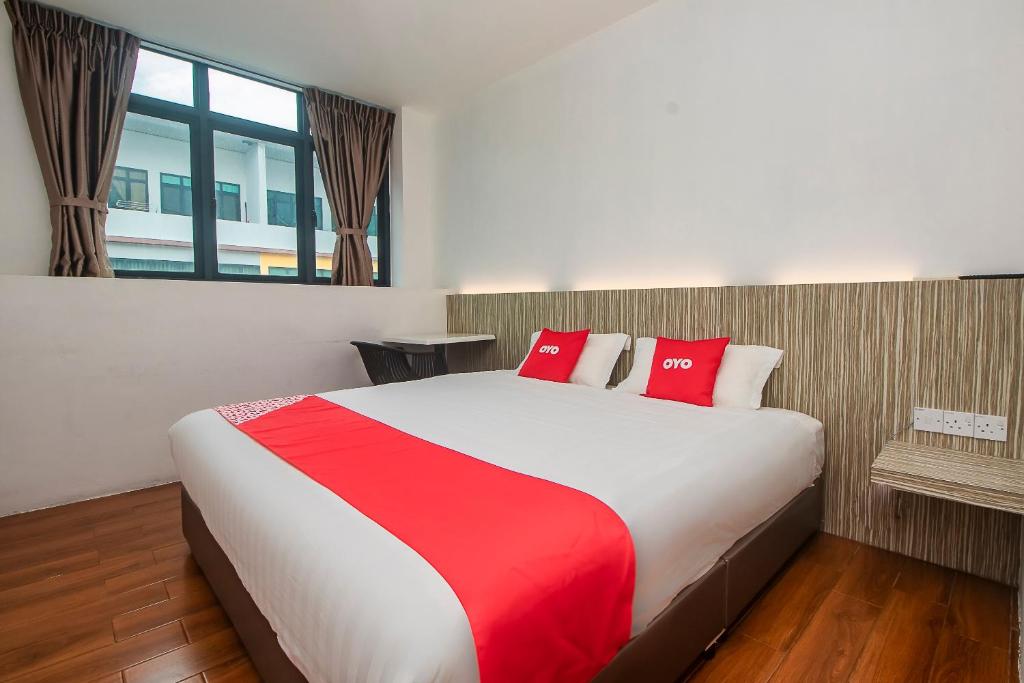 1 dormitorio con 1 cama grande con almohadas rojas en OYO 90102 7 Days Lodge en Sarikei