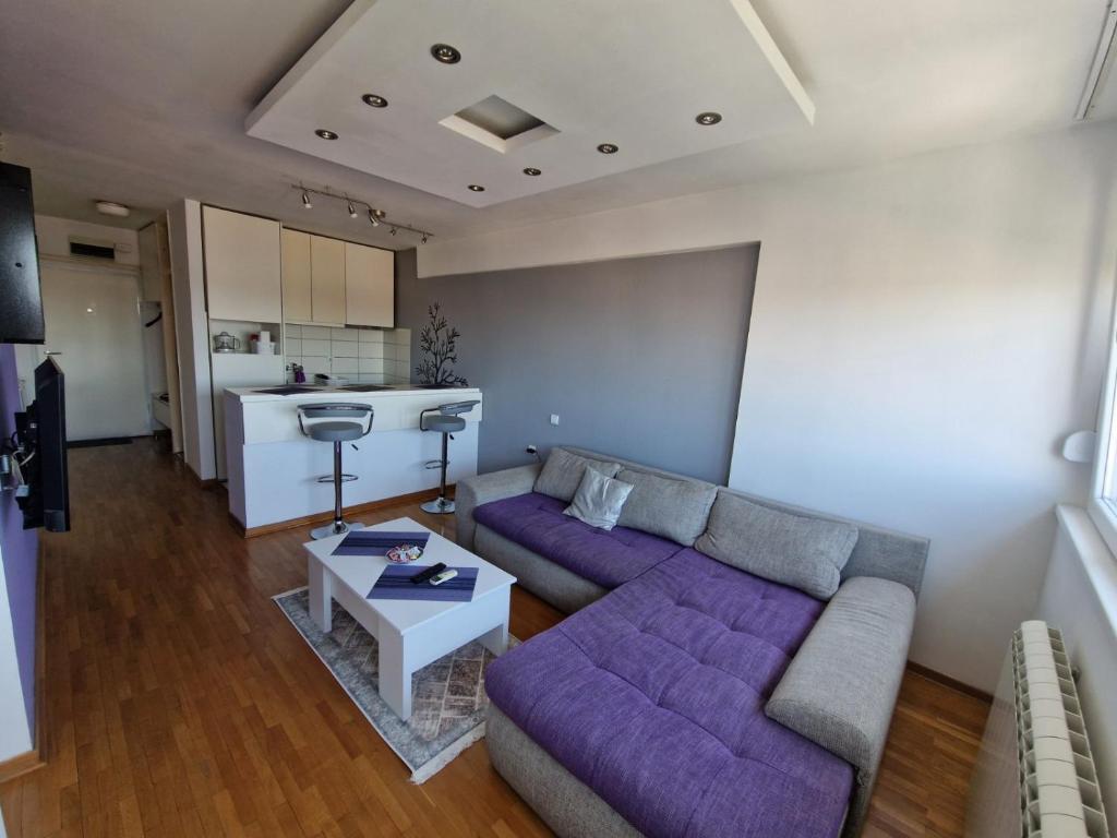 sala de estar con sofá púrpura y cocina en Harmony Apartment, en Belgrado