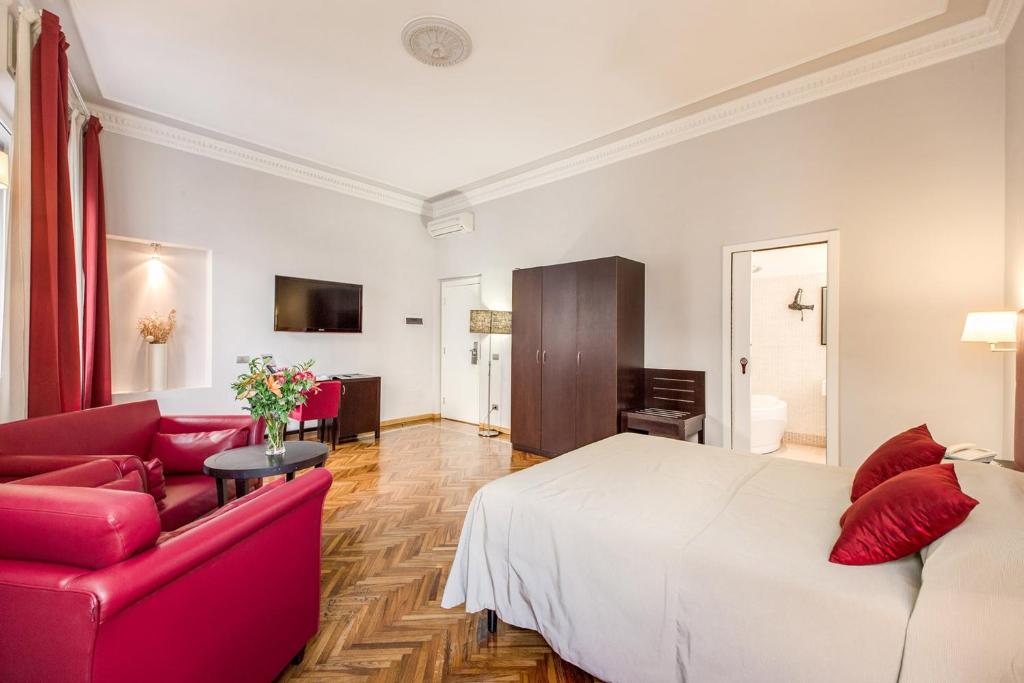 ein Schlafzimmer mit einem weißen Bett und einem roten Sofa in der Unterkunft Target Inn Rooms in Rom