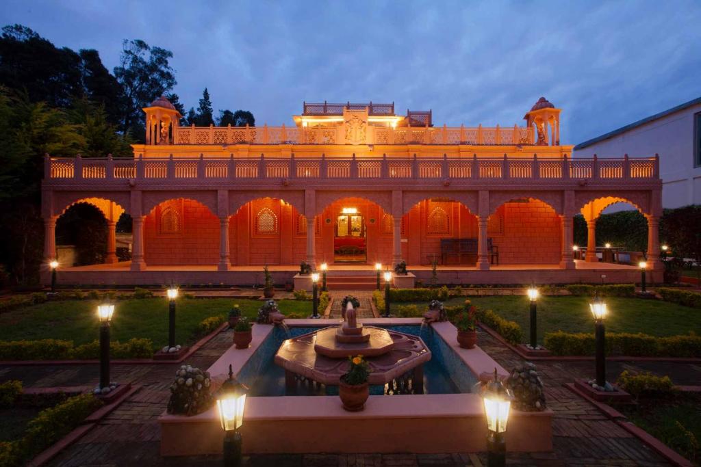 ein großes Gebäude mit einem Brunnen in einem Innenhof in der Unterkunft StayVista at Pink Palace Rajasthani Decor in Udagamandalam