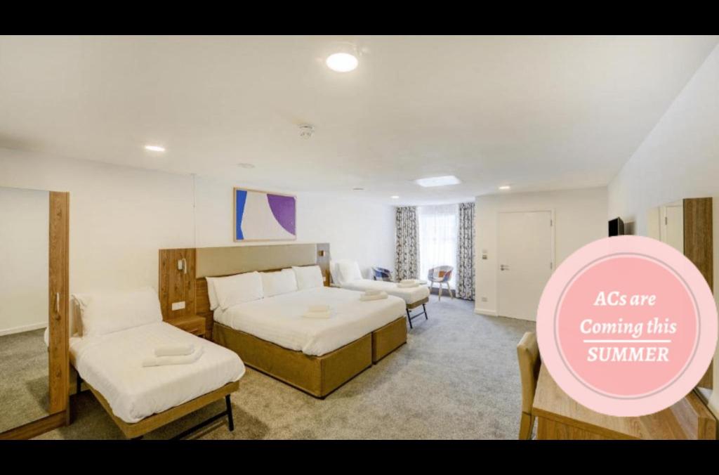 um quarto de hotel com duas camas e uma placa rosa em OYO Plymouth Central Hotel em Plymouth
