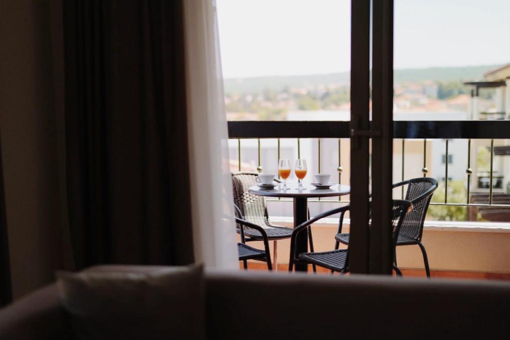 a balcony with a table with two glasses of wine at Blue Waves Resort in Malinska