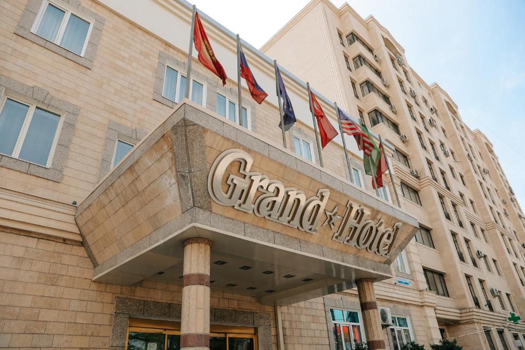 una vista frontale di un grand hotel con le bandiere di Grand Hotel a Bishkek