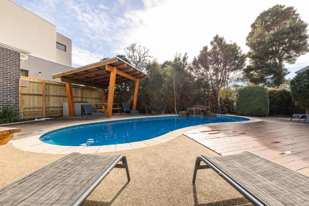 a swimming pool with a pergola and two benches at Island Oasis in Cowes