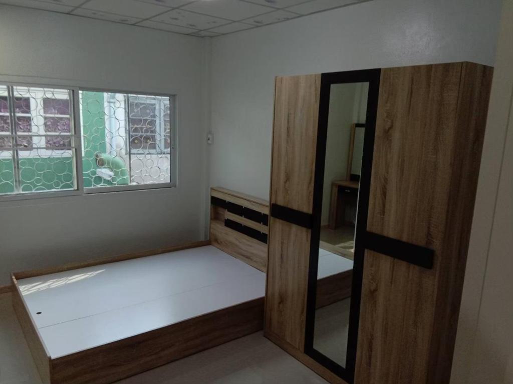 Zimmer mit einem Bett, einem Spiegel und einem Fenster in der Unterkunft 229 White House in Ban Khlong Yuan