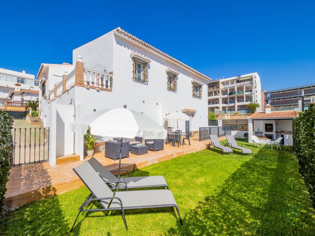een wit huis met een tuin met ligstoelen bij Cubo's Hostal William's Sunny 4 with Breakfast in Torre de Benagalbón
