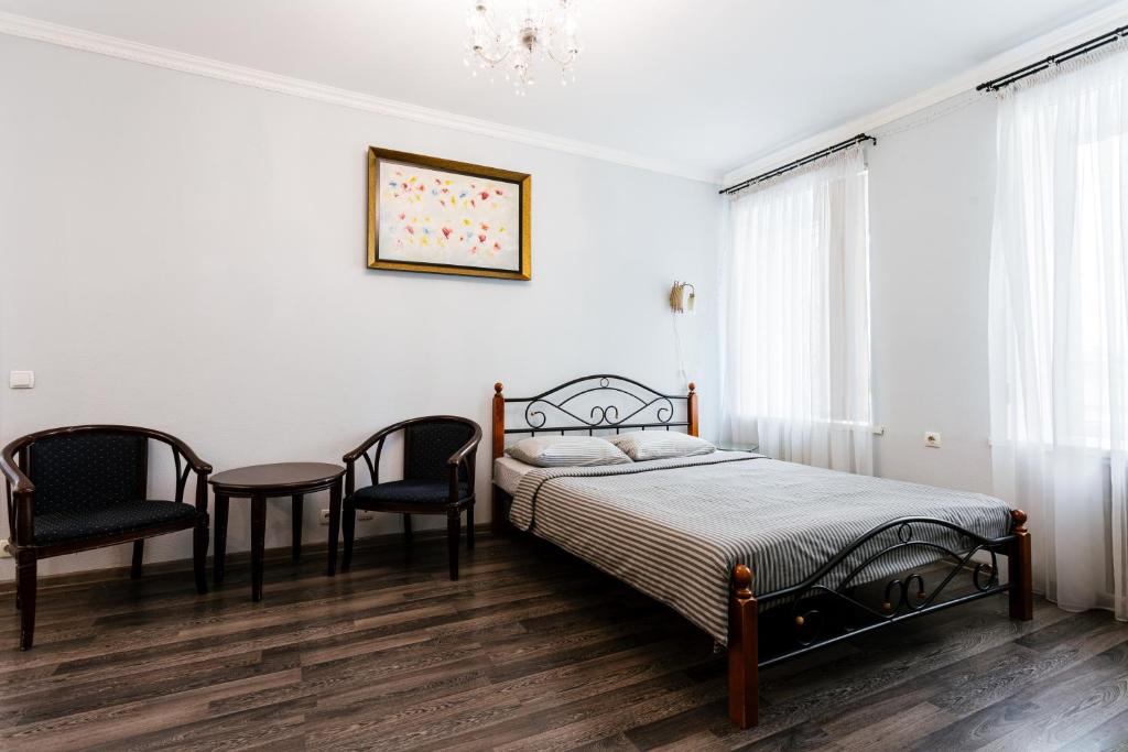 um quarto com uma cama, 2 cadeiras e uma mesa em Апартаменты в центре Киева на Бессарабской Площади 7 em Kiev