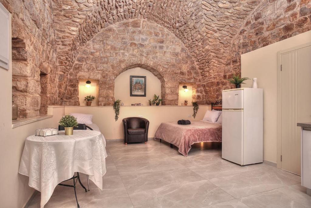 een kamer met 2 bedden, een koelkast en een tafel bij בראשית - סוויטות בוטיק בצפת העתיקה - Beresheet - Boutique Suites in the Old City in Safed