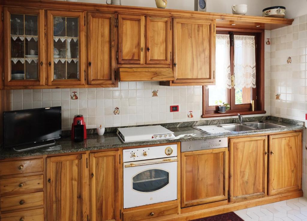 a kitchen with wooden cabinets and a sink and a stove at Rose Apartment in Aosta