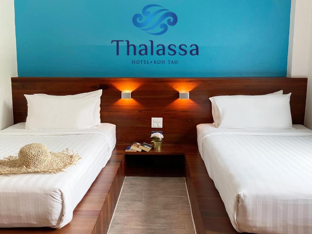 two beds in a hotel room with a sign on the wall at Thalassa - SHA Plus in Koh Tao