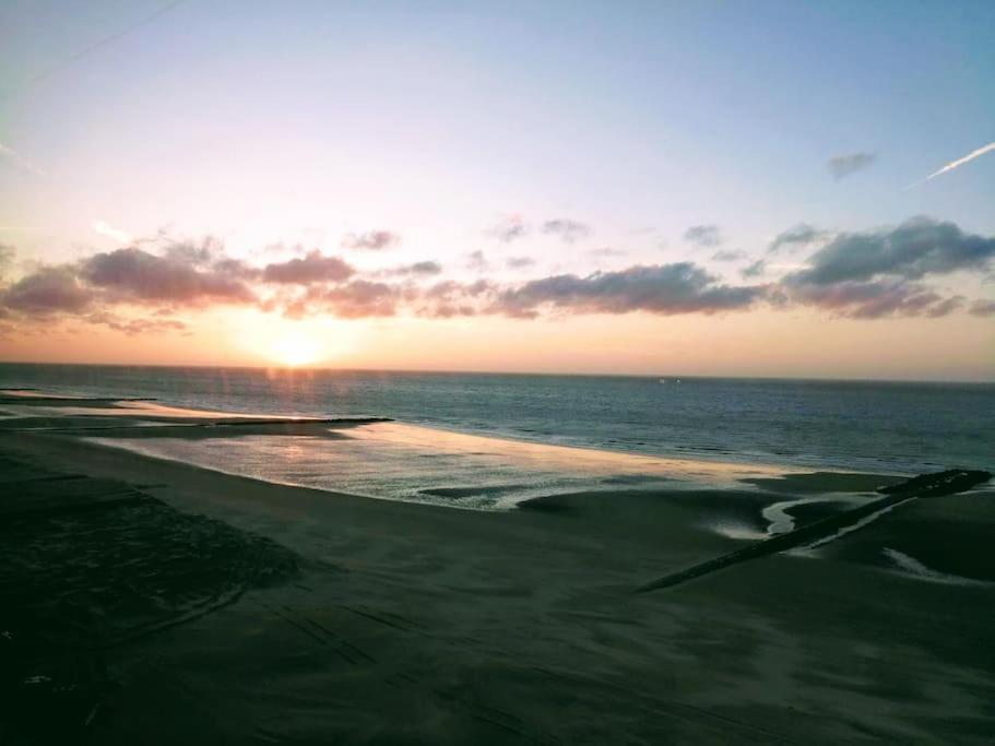 um pôr-do-sol numa praia com o oceano em Lovely n° 9 op ieder moment een prachtig zeezicht & zwembad em Middelkerke