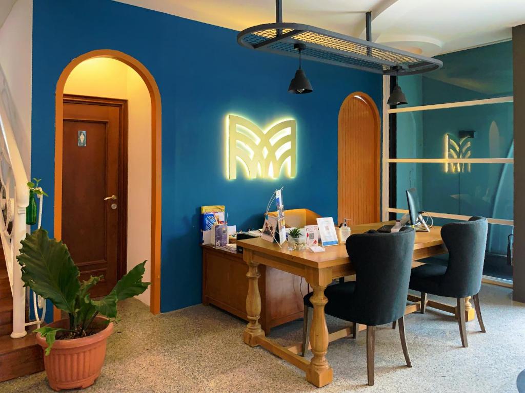 una oficina con un escritorio con sillas y una pared azul en Madina Inn Hotel, en Yogyakarta