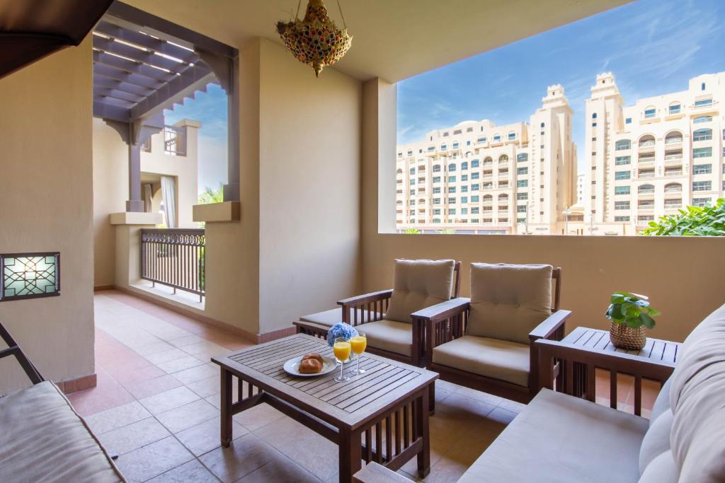 a living room with a balcony with chairs and tables at Bespoke Holiday Homes - Palm Jumeirah- 1 Bedroom Fairmont North Residence in Dubai