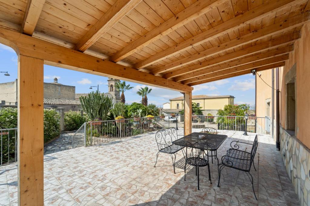 uma pérgola de madeira com uma mesa e cadeiras num pátio em Villa Mariuccia em Dolianova