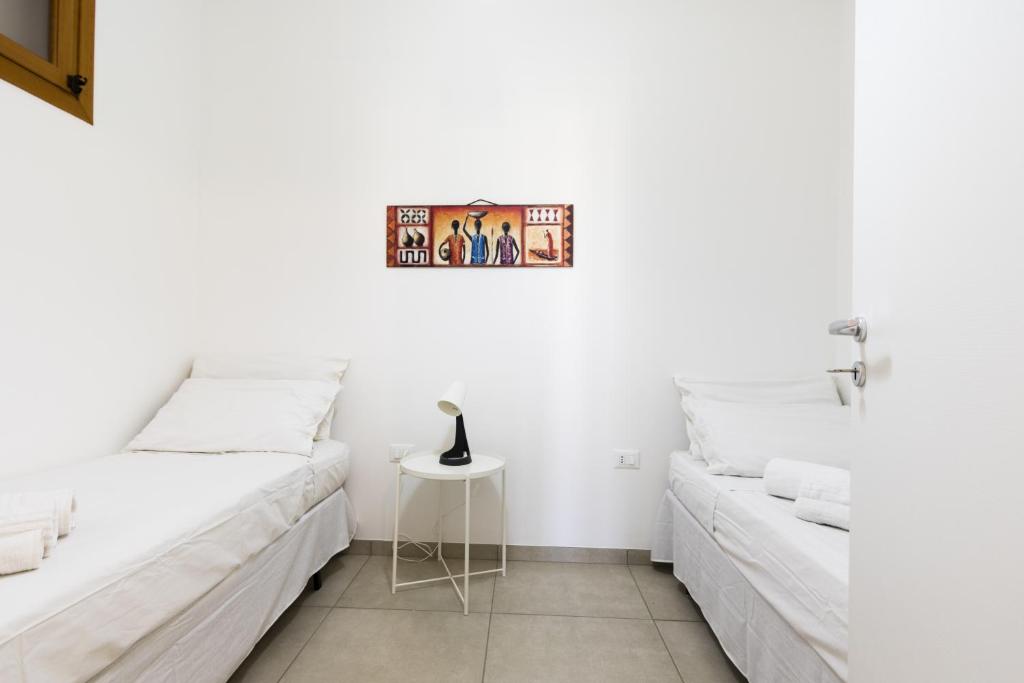 2 camas en una habitación blanca con mesa en Visitsicilia Rosetta Mare, en Alcamo Marina