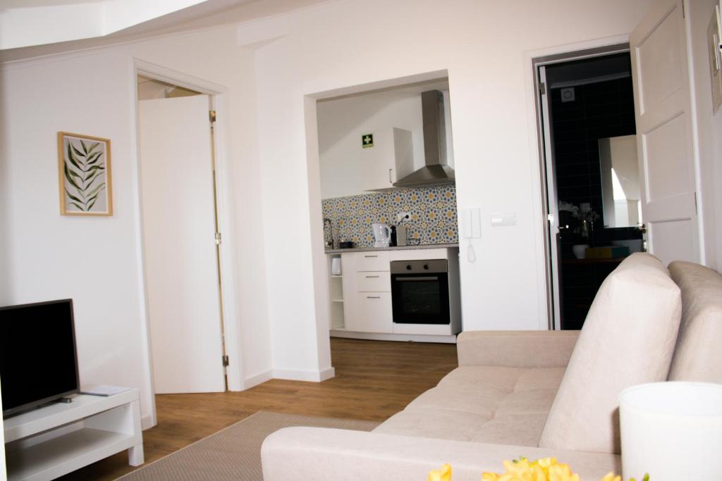 a living room with a white couch and a kitchen at Apartamento São Miguel - Santa Catarina Place in Ponta Delgada