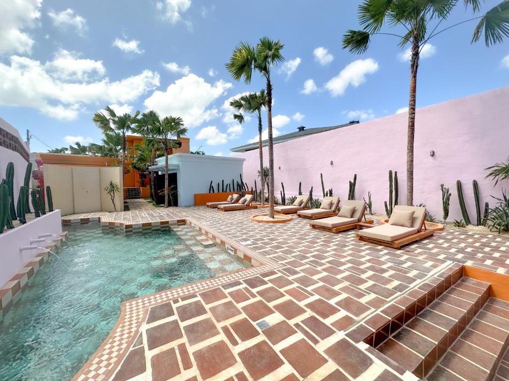 einen Pool mit Liegestühlen und Palmen in der Unterkunft El Barrio Boutique Hotel & Bar in Canggu