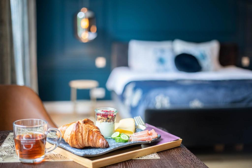 a plate of food on a table with a bed at Heuvelsuites in Oosterhout