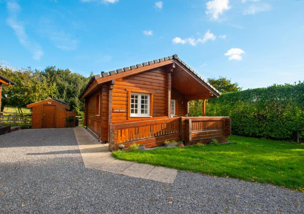 a log cabin with a porch and green grass at Silver Birch Lodge in Middleton