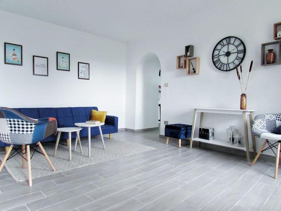 uma sala de estar com um sofá azul e um relógio na parede em Clea's holiday home em Paola
