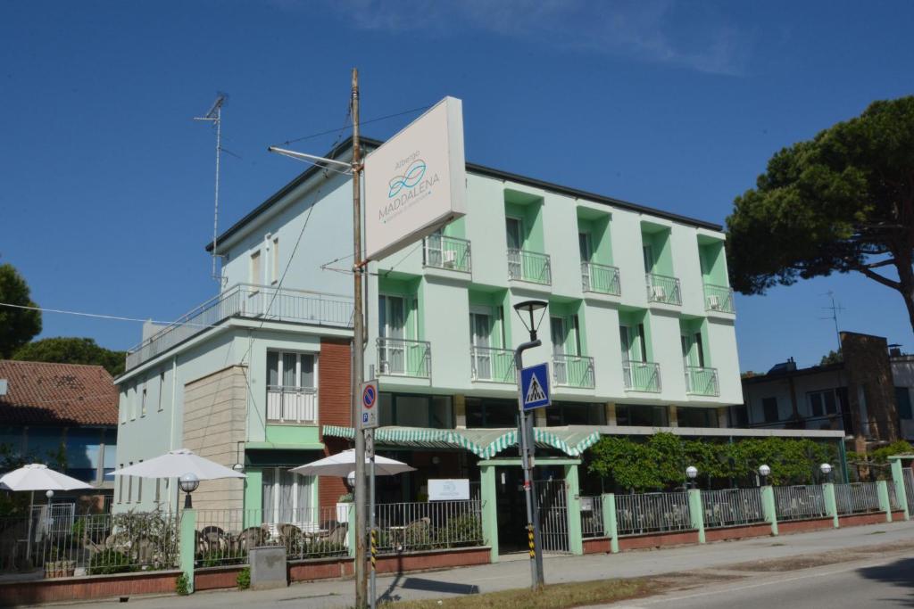 un edificio verde e bianco con un cartello di fronte di Hotel Maddalena a Marina di Ravenna