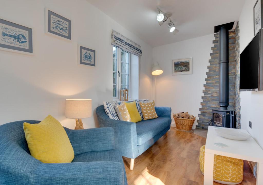 ein Wohnzimmer mit einem blauen Sofa und einem Kamin in der Unterkunft Seascape Cottage in Hinderwell