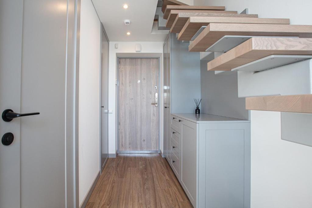 une cuisine avec des armoires blanches et un plancher en bois dans l'établissement M8 Modern Two-Floor Apartment, à Kaunas