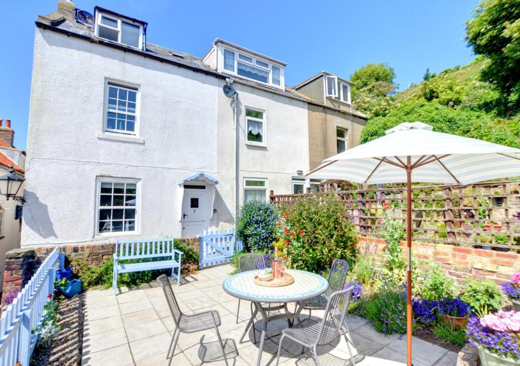 une terrasse avec une table, des chaises et un parasol dans l'établissement Seals Cottage, à Whitby