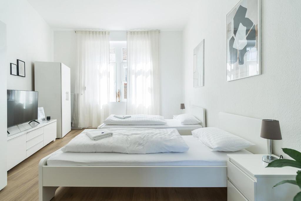 a white bedroom with two beds and a tv at Cozy Apartment in Wiesbaden in Wiesbaden