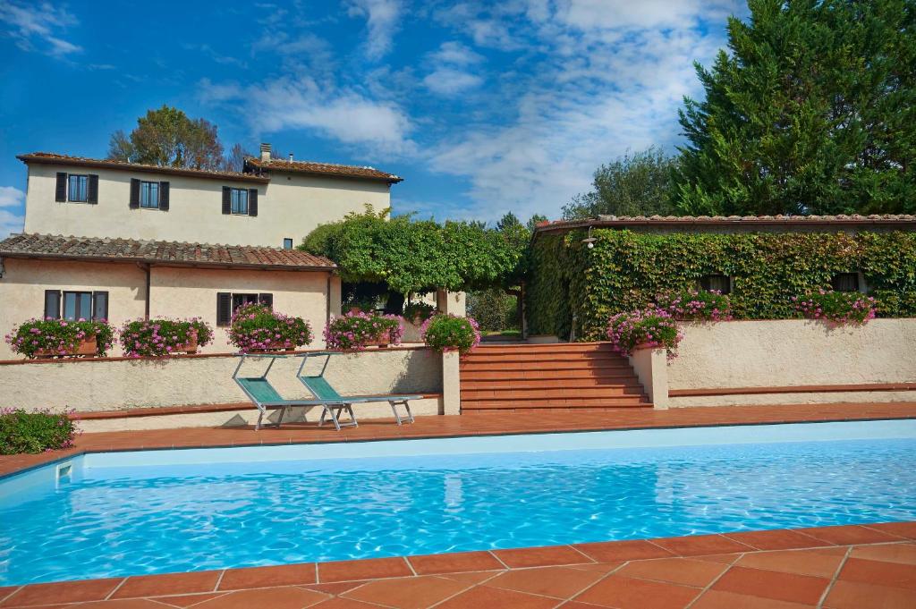 una piscina con due sedie e una casa di Colle Val D'Elsa - Agriturismo Bardeggiano a Colle Val D'Elsa