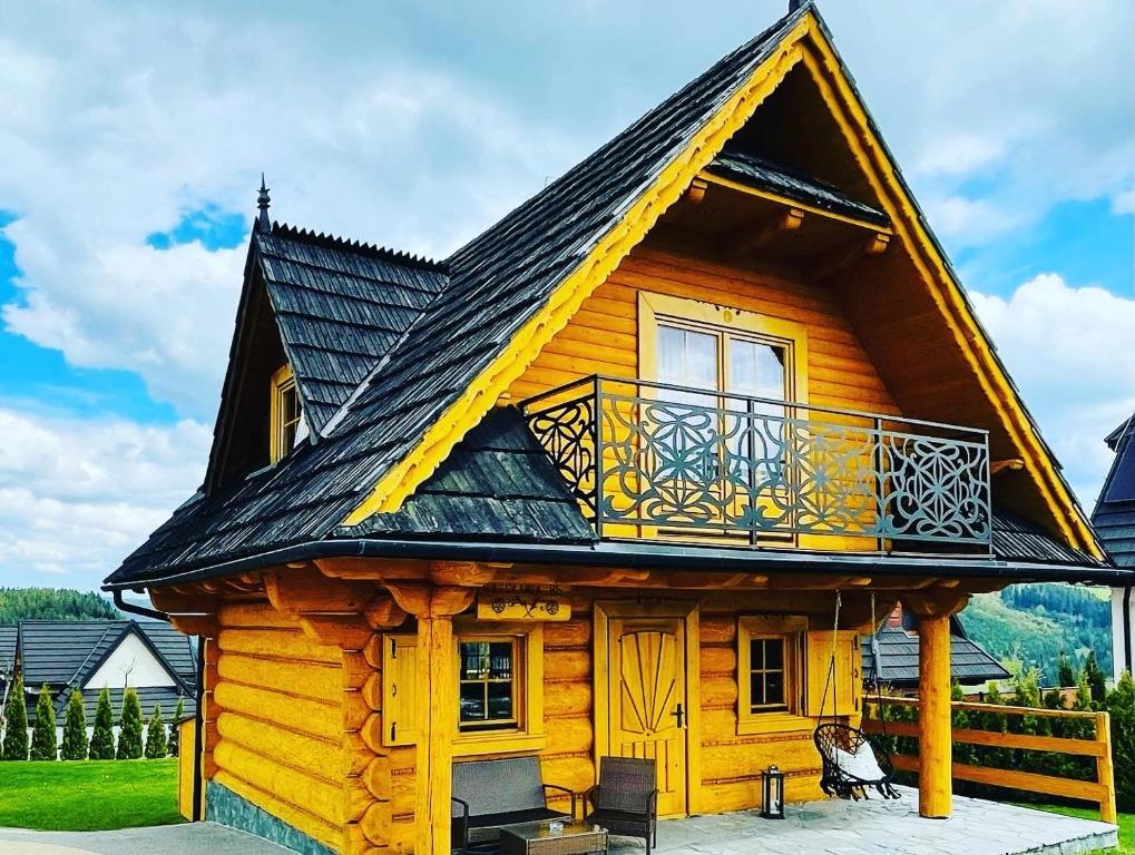 Cabaña de madera con balcón en la parte delantera en Domki Sówka, en Dursztyn