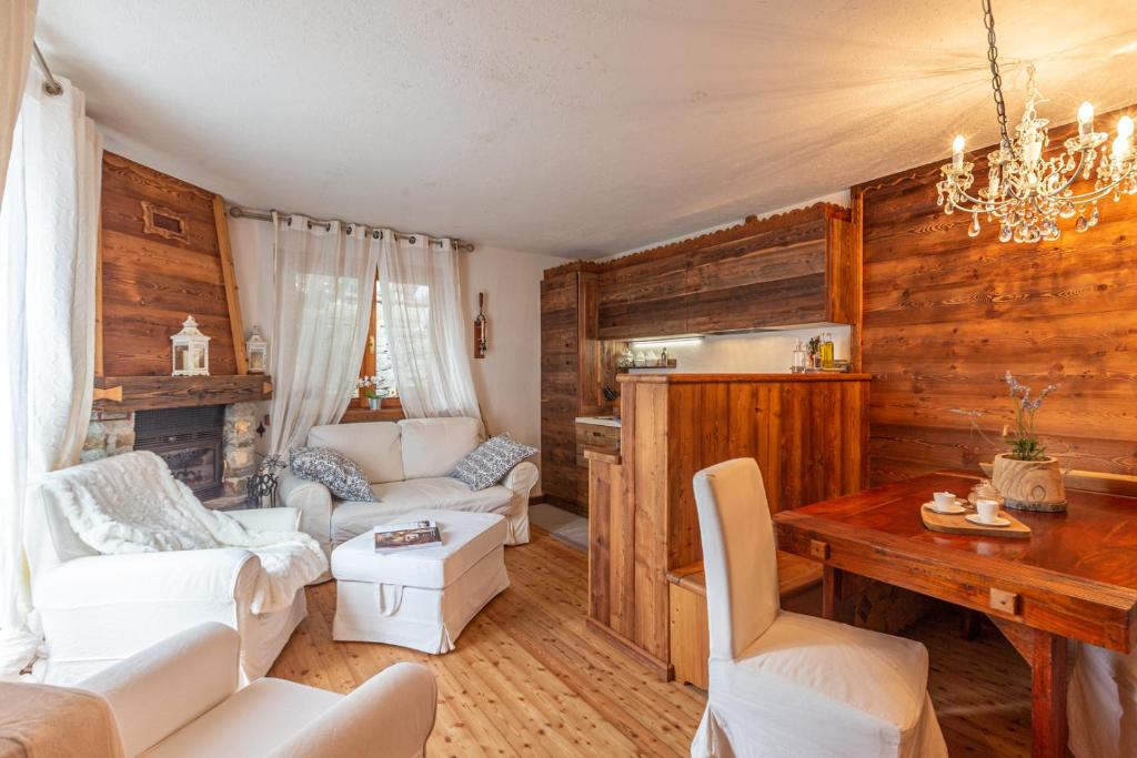 una sala de estar con muebles blancos y paredes de madera. en L'Atelier du Temps - Le Petit Refuge Appartement en Cogne