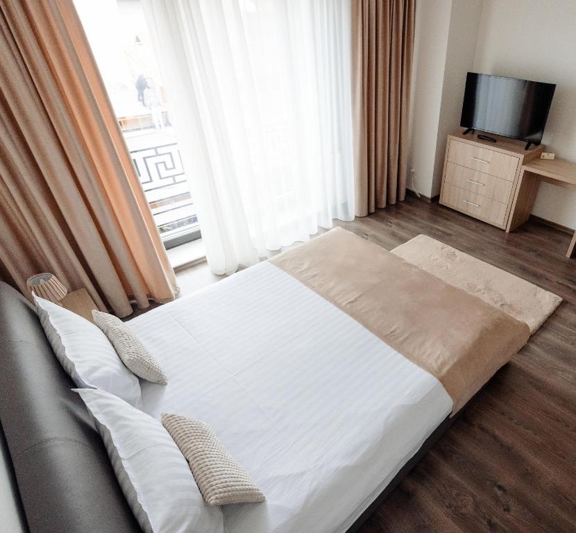 Bett in einem Zimmer mit Sofa und TV in der Unterkunft Aparthotel Punct pe i in Sighetu Marmaţiei