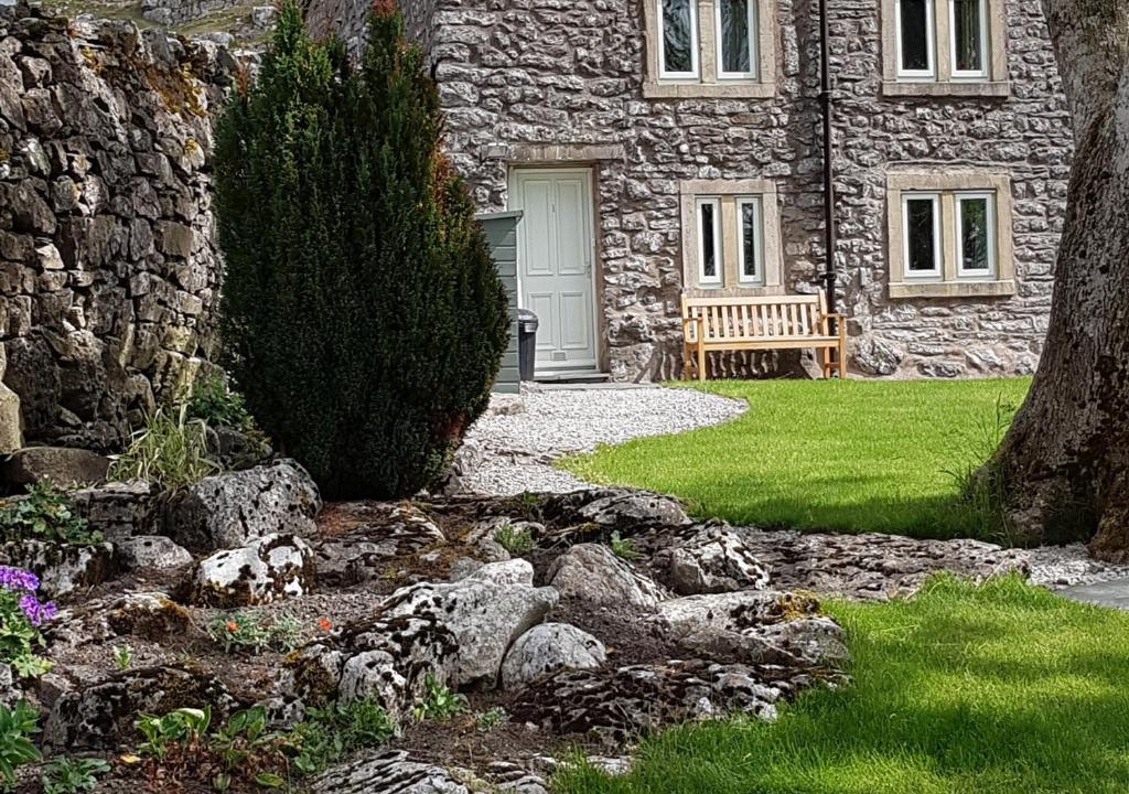una casa de piedra con un banco delante en Scar End Cottage en Ingleton 