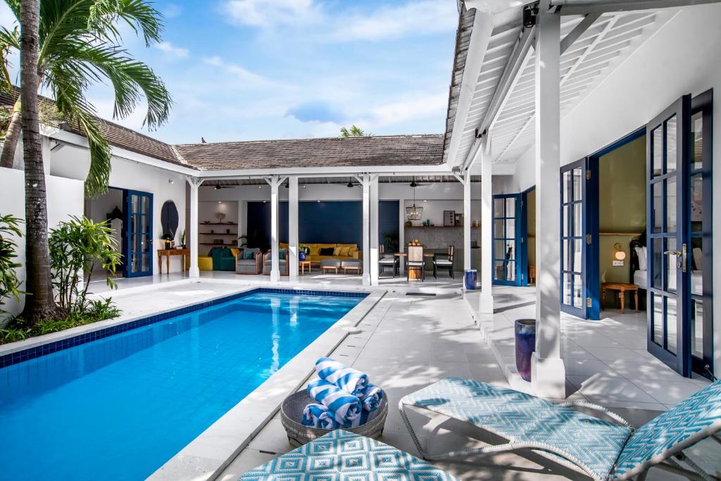 a swimming pool in a villa with chairs and a house at The Beach House in Canggu