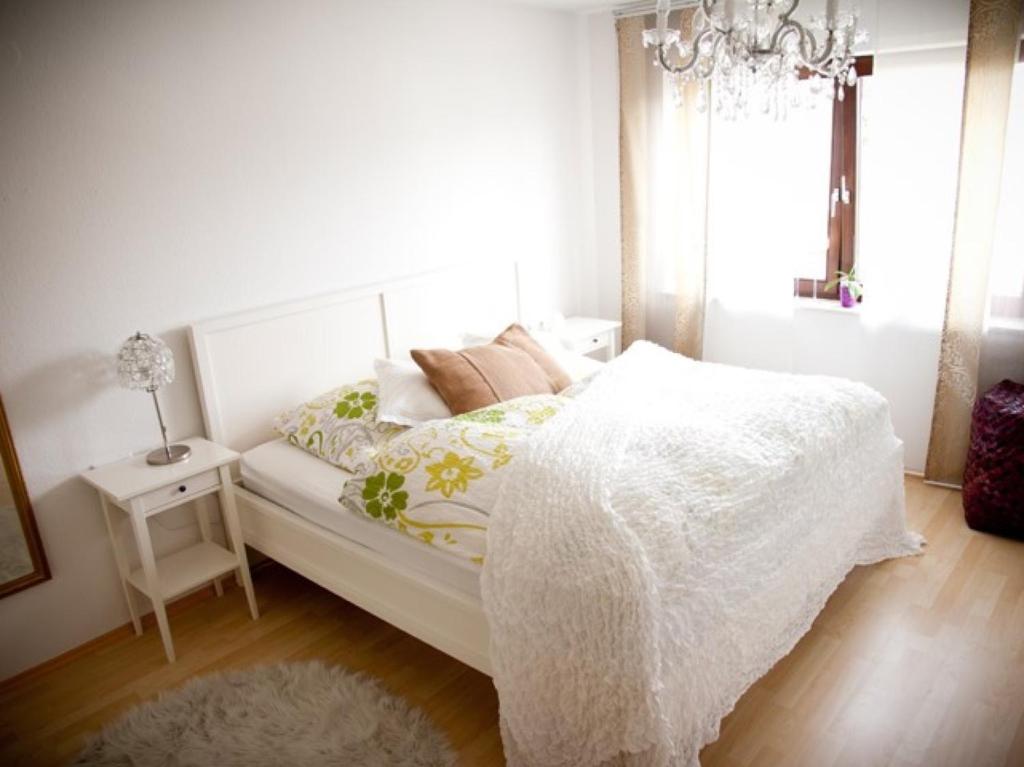 a bedroom with a white bed and a chandelier at Casa Sofia in Friedrichshafen
