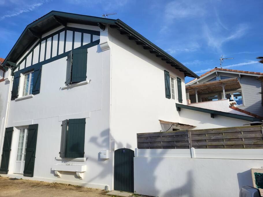 a white house with green shutters on it at Appartement sur cour privative in Capbreton