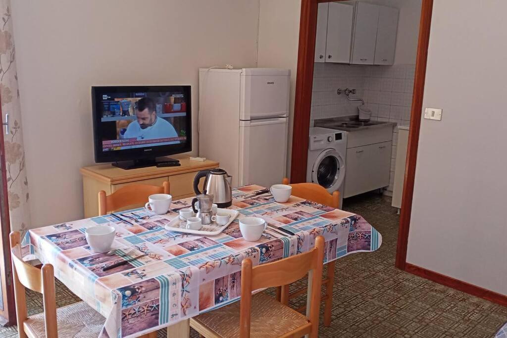 eine Küche mit einem Tisch und einem TV sowie einem Tisch und Stühlen in der Unterkunft appartamento Walter in centro in Rosolina Mare