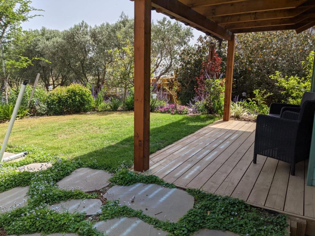 a wooden deck with two chairs on a lawn at Provence in the Valley in Kefar Barukh
